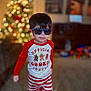 child, boy, sunglasses, pajamas, red_and_white, striped_pants, indoor, christmas_tree, holiday, toy, carpet, cute, smiling, standing, young_child, face, hair, clothing, home, festive