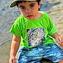 Billie joined the competition — help win amazing prizes! child, toddler, boy, hat, camo_hat, green_tshirt, fish_graphic, shorts, water, rock, outdoor, summer, nature, portrait, face, expression, sitting, casual_clothing, daylight, curious