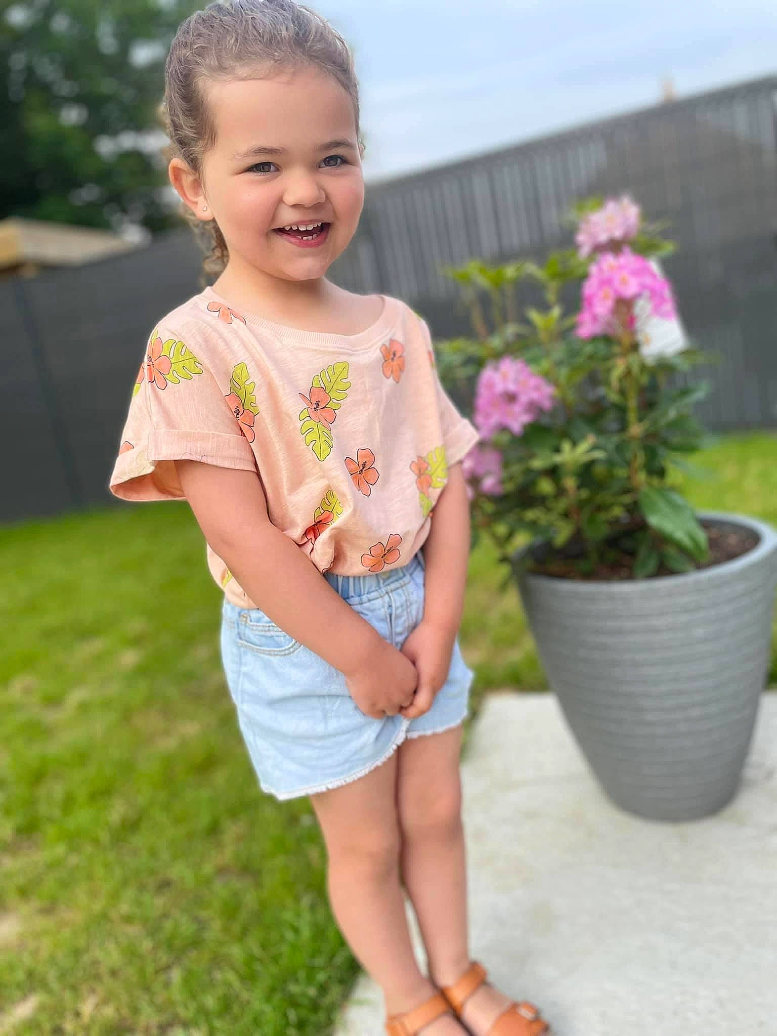 Lisa participe au concours pour gagner de l'argent avec cette photo : baby_toddler_clothing, clothing, facial_expression, flower, flowerpot, grass, happy, head, houseplant, human_body, joy, leg, leisure, people_in_nature, person, pink, plant, shorts, sleeve, smile