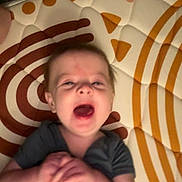 Brynlee is registered to the contest to win money with this photo: baby, infant, child, mat, pattern, clothing, hands, mouth_open, lying_down, face, expression, indoor, blur, skin, hair, person, young_child, play_area, colorful, candid