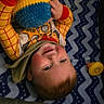 Arnold is registered to the contest to win money with this photo: baby, child, smiling, toy, knitted_doll, blue_blanket, zigzag_pattern, woody_costume, infant, nursery, playful, happy, clothing, hand, face, head, lying_down, bed, cushion, cozy
