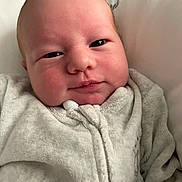 Markus is registered to the contest to win money with this photo: baby, infant, face, smile, blanket, clothing, closeup, cheeks, newborn, soft, cozy, portrait, human, cute, sleepwear, indoors, child, skin, expression, warm