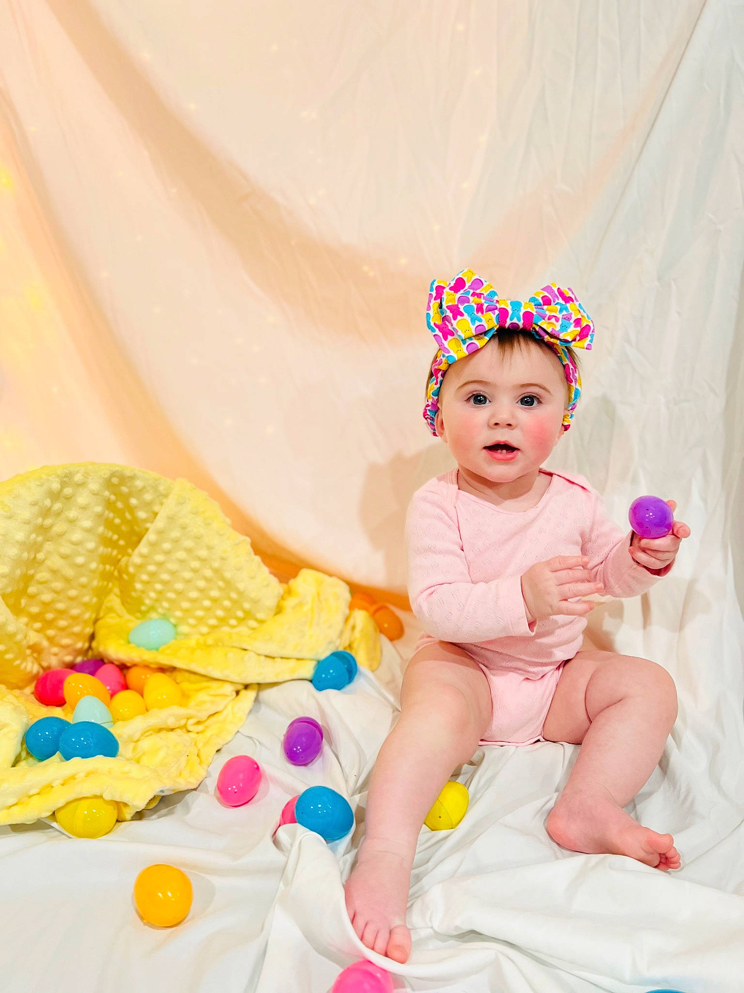 Madeline joined the competition — help win amazing prizes! baby, baby_toddler_clothing, child, comfort, costume_hat, event, fashion_accessory, finger, fun, happy, headgear, headpiece, linens, magenta, pattern, peach, person, pink, sitting, surprise