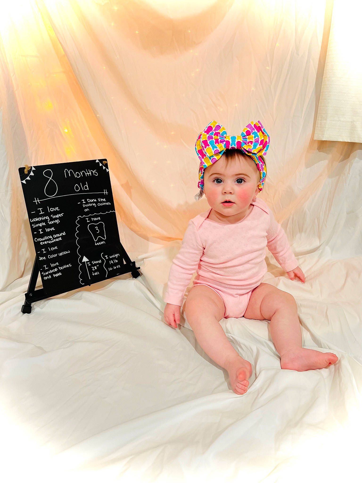 Madeline joined the competition — help win amazing prizes! baby, baby_toddler_clothing, bedding, child, comfort, design, dress, eye, fashion_accessory, happy, headpiece, headwear, linens, pattern, peach, person, pink, product, sitting, sleeve