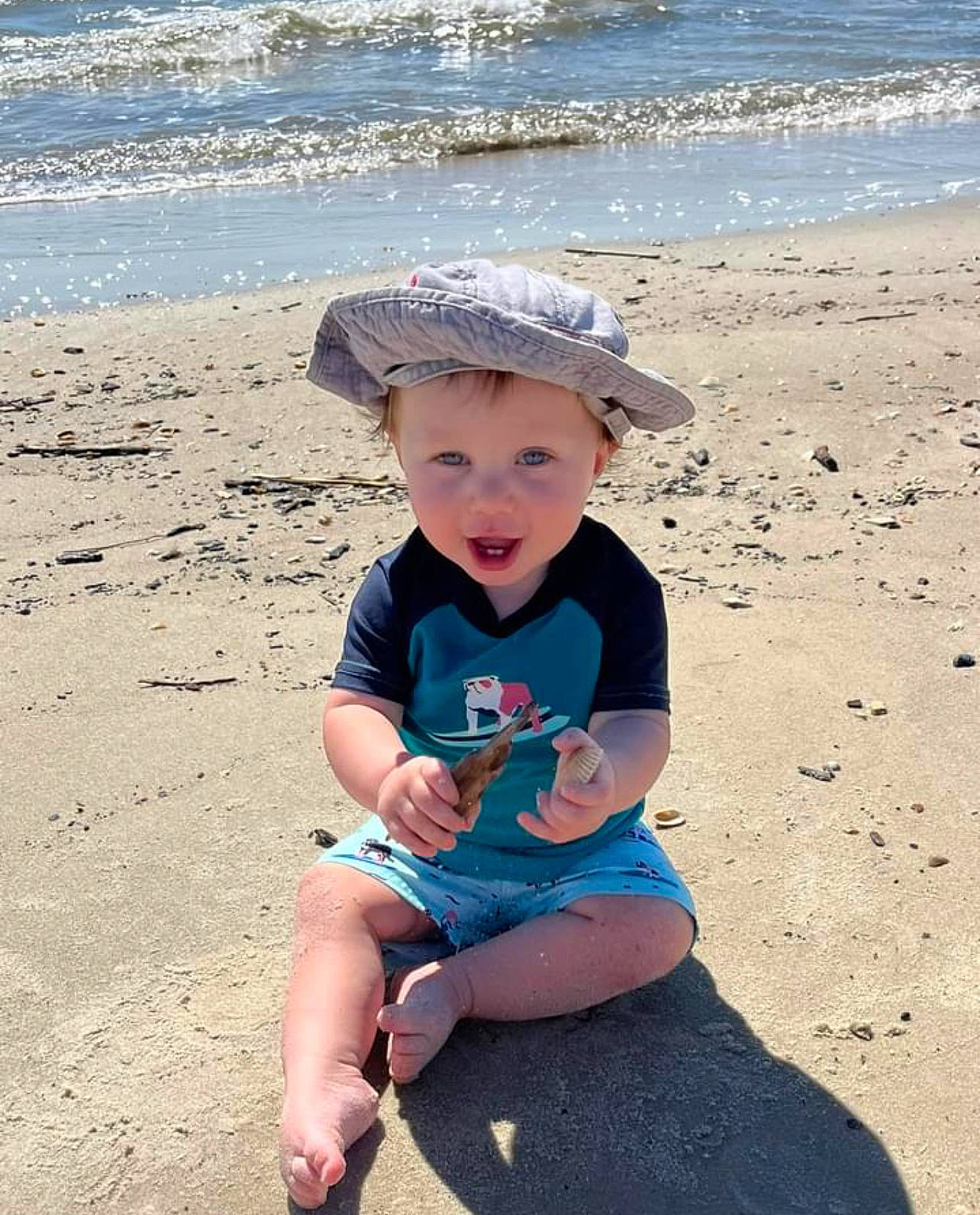 Cash is registered to the contest to win money with this photo: azure, beach, body_of_water, cap, child, fun, happy, hat, headwear, landscape, leisure, people, people_on_beach, person, sand, shore, smile, sun_hat, t_shirt, toddler