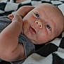 Lynnwood is registered to the contest to win money with this photo: baby, infant, face, blue_eyes, skin, blanket, checkered_pattern, close_up, portrait, newborn, cute, expression, lying_down, soft_light, arm, hand, clothing, indoors, head, child