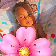 Kynlee is registered to the contest to win money with this photo: baby, child, curly_hair, tongue_out, blanket, pink_towel, colorful_pattern, monkey_print, outdoor, sunlight, shadow, playful, infant, cute, smiling, portrait, relaxing, person, flower_emoji, skin