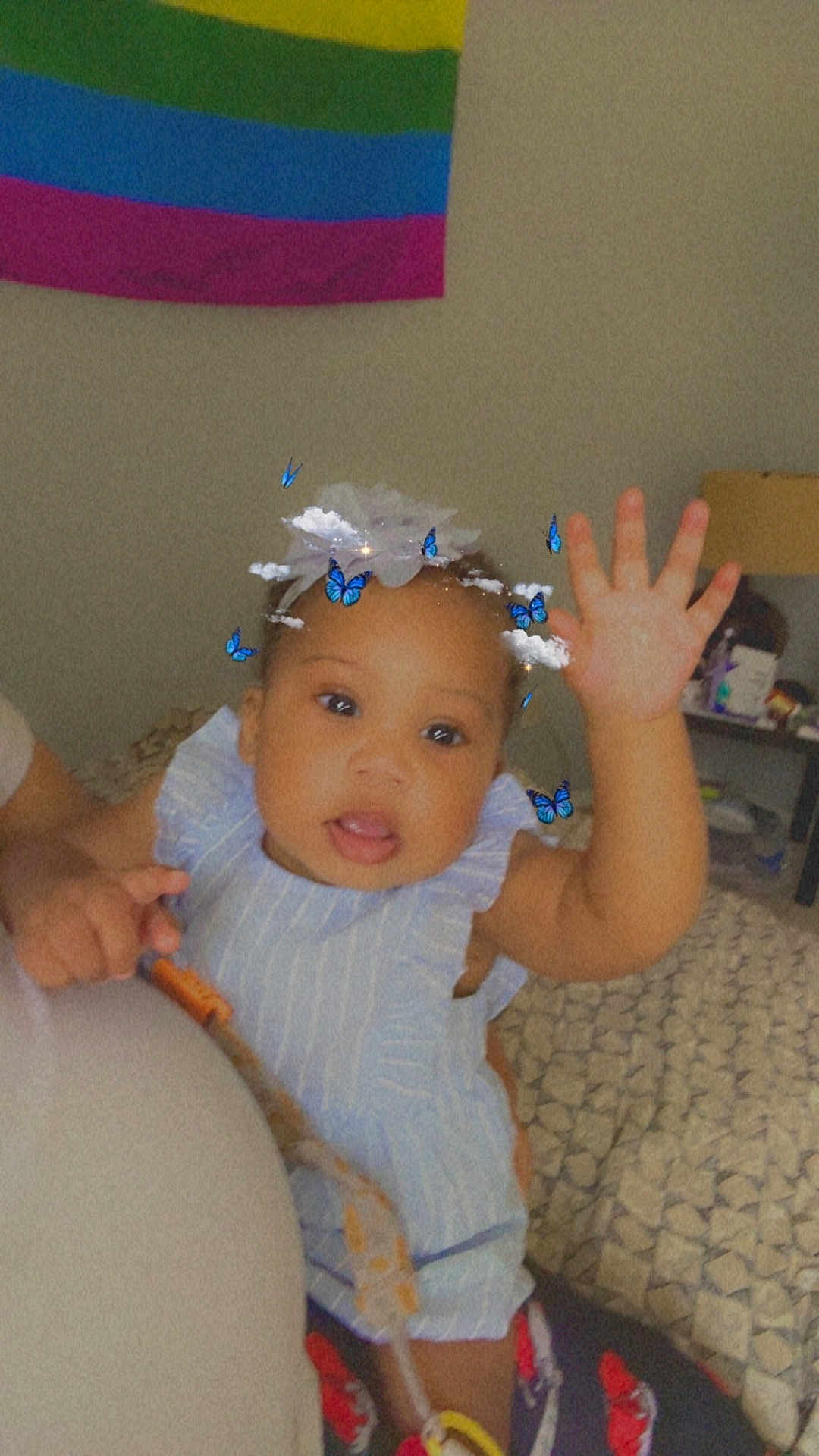 Neeah joined the competition — help win amazing prizes! baby, bed, blanket, blue_outfit, butterflies, child, clouds, cute, filter, furniture, hand, happy, headwear, indoor, infant, person, portrait, rainbow_flag, smiling, waving