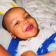 Imran joined the competition — help win amazing prizes! baby, smiling, blanket, blue, crochet, bed, bedding, infant, child, face, happy, person, portrait, sleepwear, lying_down, cuddly, cute, indoors, toddler, relaxed