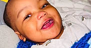 Imran joined the competition — help win amazing prizes! baby, bed, bedding, blanket, blue, child, crochet, cuddly, cute, face, happy, indoors, infant, lying_down, person, portrait, relaxed, sleepwear, smiling, toddler