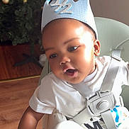 Imran joined the competition — help win amazing prizes! baby, birthday_crown, child, christmas_tree, crown, cute, face, festive, happy, high_chair, holiday, home, indoor, portrait, seatbelt, smiling, sunlight, toddler, white_shirt, wood_floor