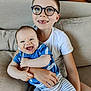Oscar a rejoint le concours — aidez-le/la à gagner de superbes lots ! child, baby, sibling, glasses, smiling, laughing, couch, indoor, tshirt, striped_pants, blue_shirt, happy, family, portrait, person, seated, comfort, home, cute, affection