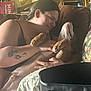 person, dog, couch, tattoo, indoors, affection, cuddling, brown_furniture, relaxed, home, love, comfort, casual_clothing, black_hair, pet, living_room, hand, smile, resting, closeup