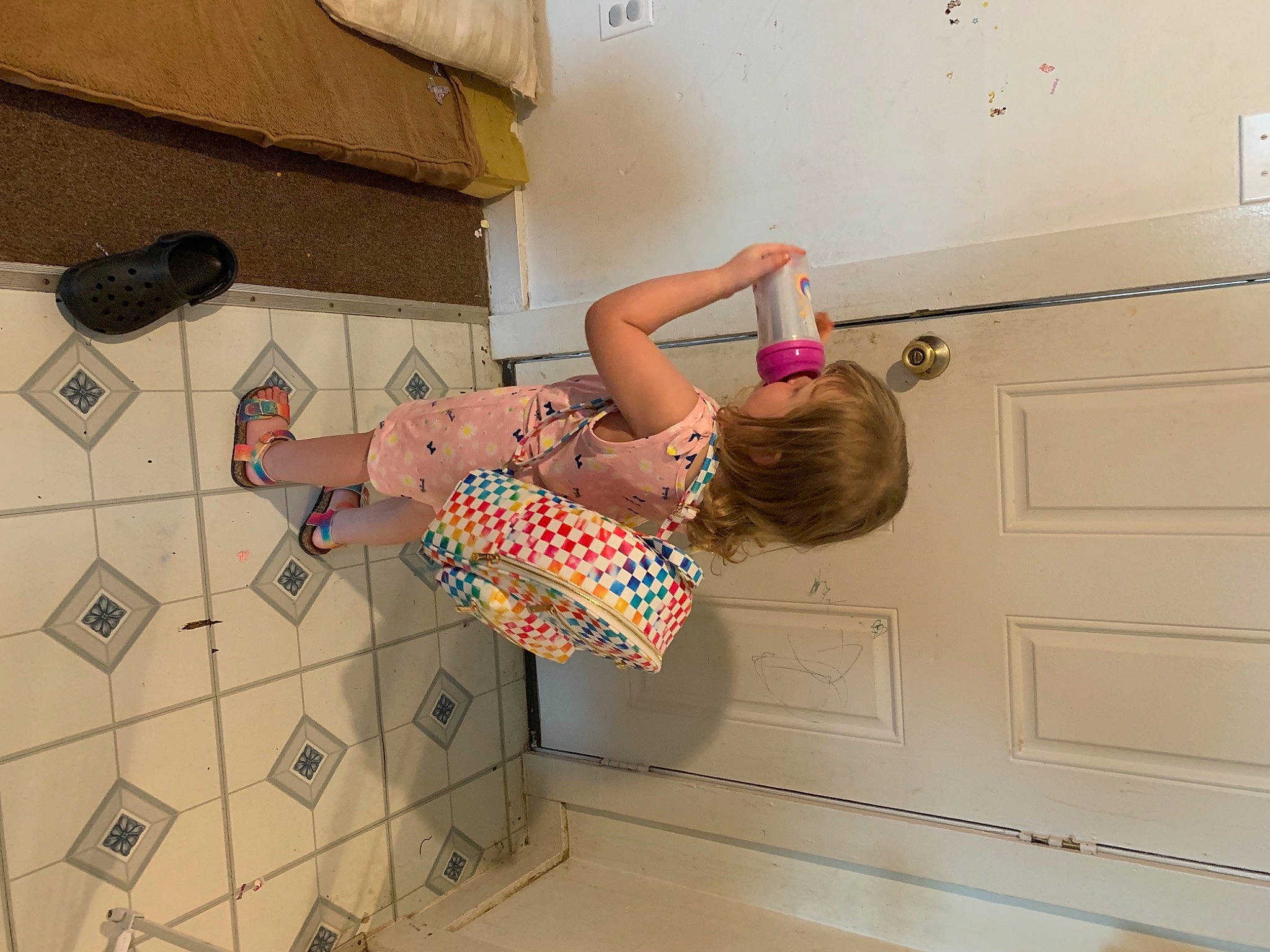Sophia is registered to the contest to win money with this photo: ceiling, comfort, door, elbow, floor, flooring, fun, hardwood, human_leg, joint, knee, pattern, person, room, sandal, sneakers, thigh, toddler, waist, wall