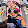 Isabelle is registered to the contest to win money with this photo: baby, sunglasses, bow, headband, stroller, seatbelt, blue_clothing, striped_clothing, pink_cup, hand, face, child, sunlight, shadow, cute, infant, accessory, fashion, outdoor, portrait