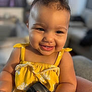 Isabelle is registered to the contest to win money with this photo: toddler, child, smiling, yellow_dress, camera_accessory, indoor, portrait, happy, cute, baby, face, hand, furniture, living_room, skin, curly_hair, person, closeup, sitting, bright