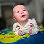 baby, child, close_up, colorful, curious, cute, expression, eyes, face, hands, head, indoors, infant, lying_down, mouth, pajamas, play_mat, skin, soft_focus, young
