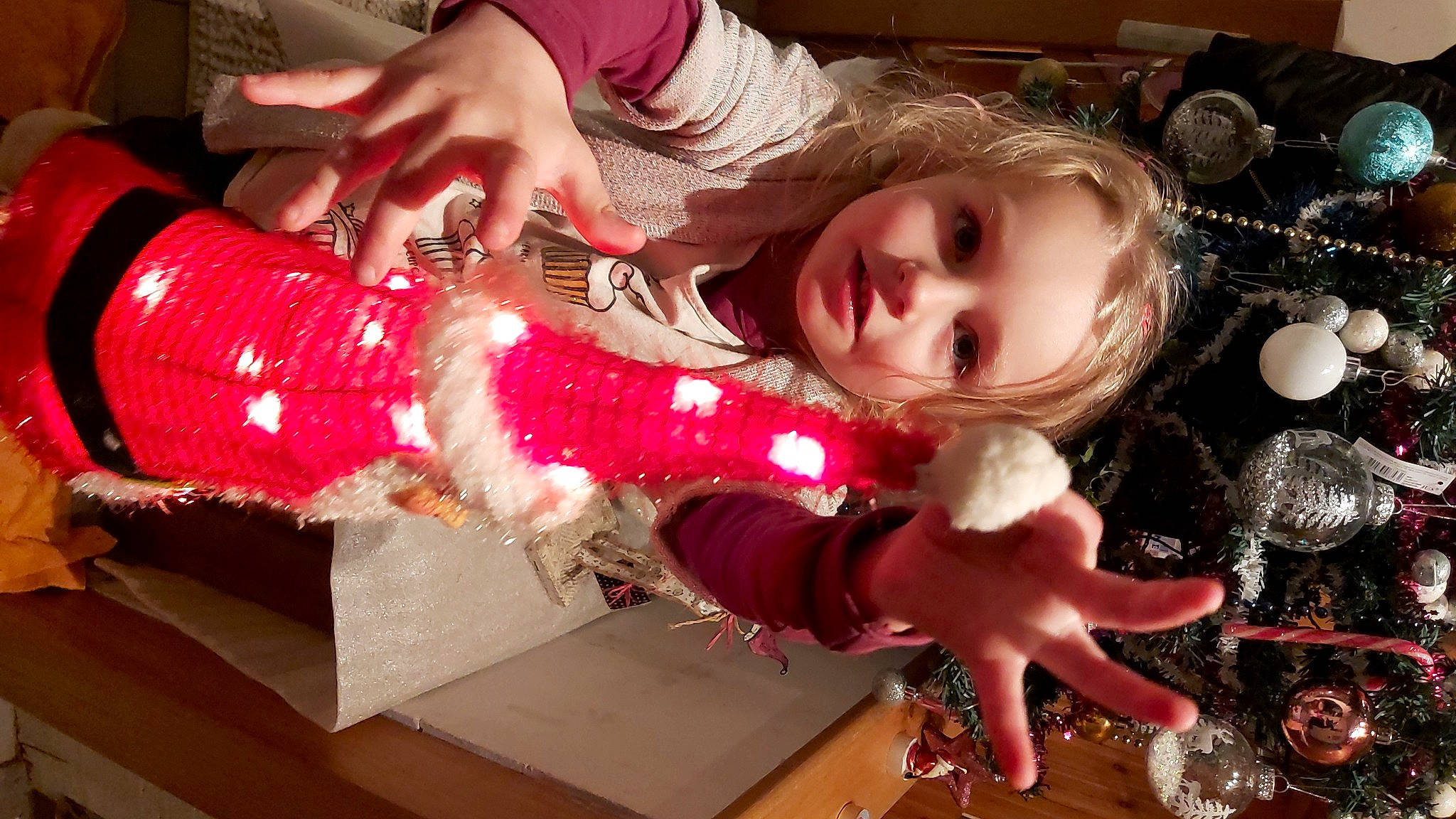 Délia participe au concours pour gagner de l'argent avec cette photo : arm, child, christmas, christmas_decoration, christmas_eve, christmas_ornament, dress, event, finger, fun, hand, happy, holiday, human_leg, magenta, nail, person, pink, smile, toddler