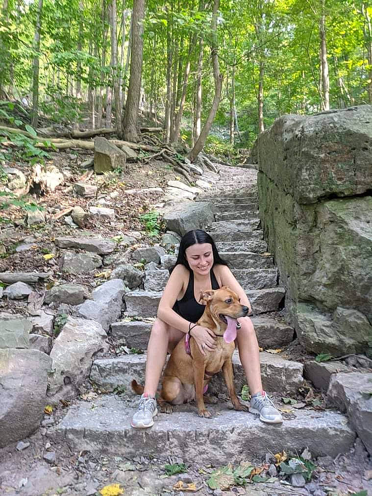 Karma is registered to the contest to win money with this photo: adventure, bedrock, carnivore, fawn, forest, grass, human_leg, landscape, leisure, natural_landscape, outcrop, people_in_nature, plant, recreation, smile, thigh, tree, trunk, wood, woodland