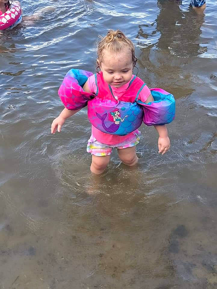 Skyla is registered to the contest to win money with this photo: baby, baby_toddler_clothing, bathing, beach, child, fun, inflatable, joy, lake, leisure, lifejacket, ocean, outdoor_recreation, person, personal_protective_equipment, play, recreation, sand, toddler, water
