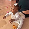 adult, baby, balls, bow, child, cute, floor, happy, home, hoodie, indoor, orange_toy, person, pink_wall, playtime, sitting, toddler, toy, white_clothing, wooden_floor