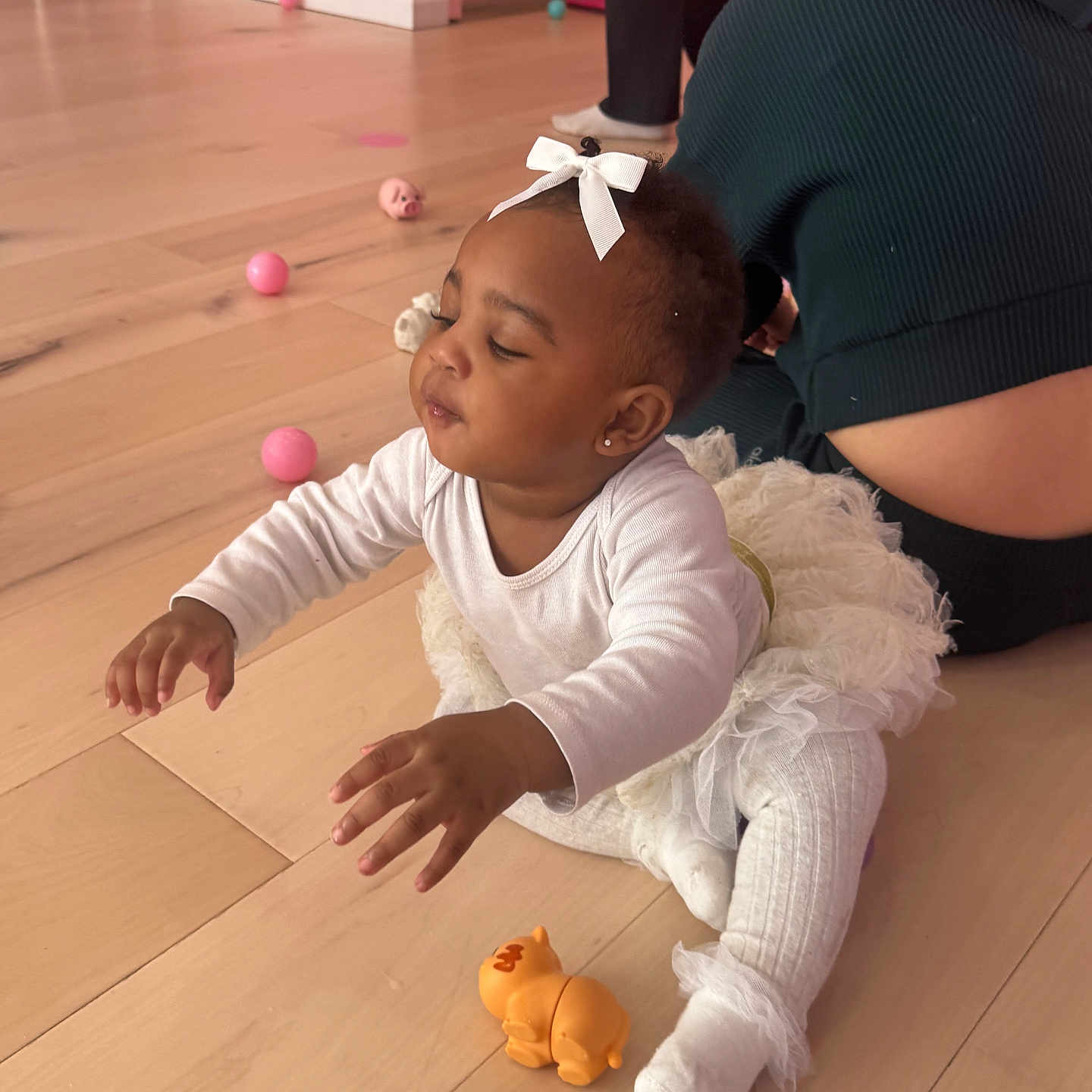 Keyurii joined the competition — help win amazing prizes! adult, baby, balls, bow, child, cute, floor, happy, home, hoodie, indoor, orange_toy, person, pink_wall, playtime, sitting, toddler, toy, white_clothing, wooden_floor