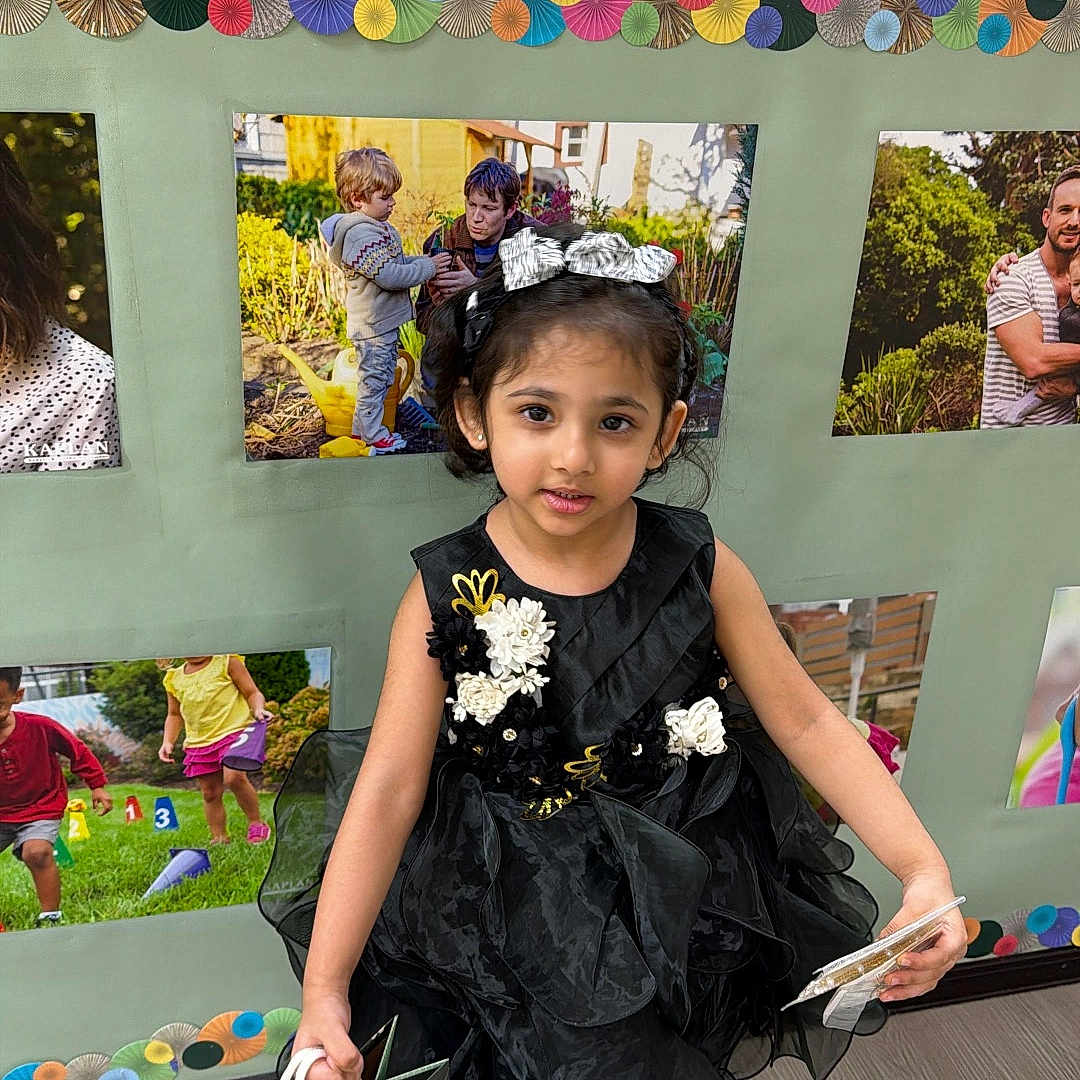 Nimal joined the competition — help win amazing prizes! child, girl, dress, black_dress, headband, gift_bag, indoor, floor, photography, portrait, smile, celebration, party, decoration, colorful, wall, photo_display, young, person, footwear