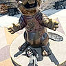 Ashoka joined the competition — help win amazing prizes! dog, statue, bronze, outdoor, sunlight, concrete, beaver, leash, happy, pet, sculpture, building, brick_wall, shadow, smiling, animal, sidewalk, urban, daytime, cuteness
