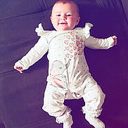 Laïa participe au concours pour gagner de l'argent avec cette photo : baby, infant, smiling, onesie, elephant, hearts, white_clothing, socks, lace, couch, furniture, indoor, child, person, happy, cute, resting, lying_down, soft_lighting, cozy