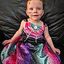 child, red_hair, face_paint, dress, spider_web, bat, moon, smiling, sitting, couch, leather, colorful, costume, portrait, indoors, young_child, happy, cute, holiday, celebration