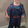 Willow is registered to the contest to win money with this photo: child, red_hair, smile, overalls, striped_shirt, indoor, wooden_floor, yellow_socks, standing, happy, face, person, window_sill, wall, flooring, cute, young_child, hair_buns, clothing, casual