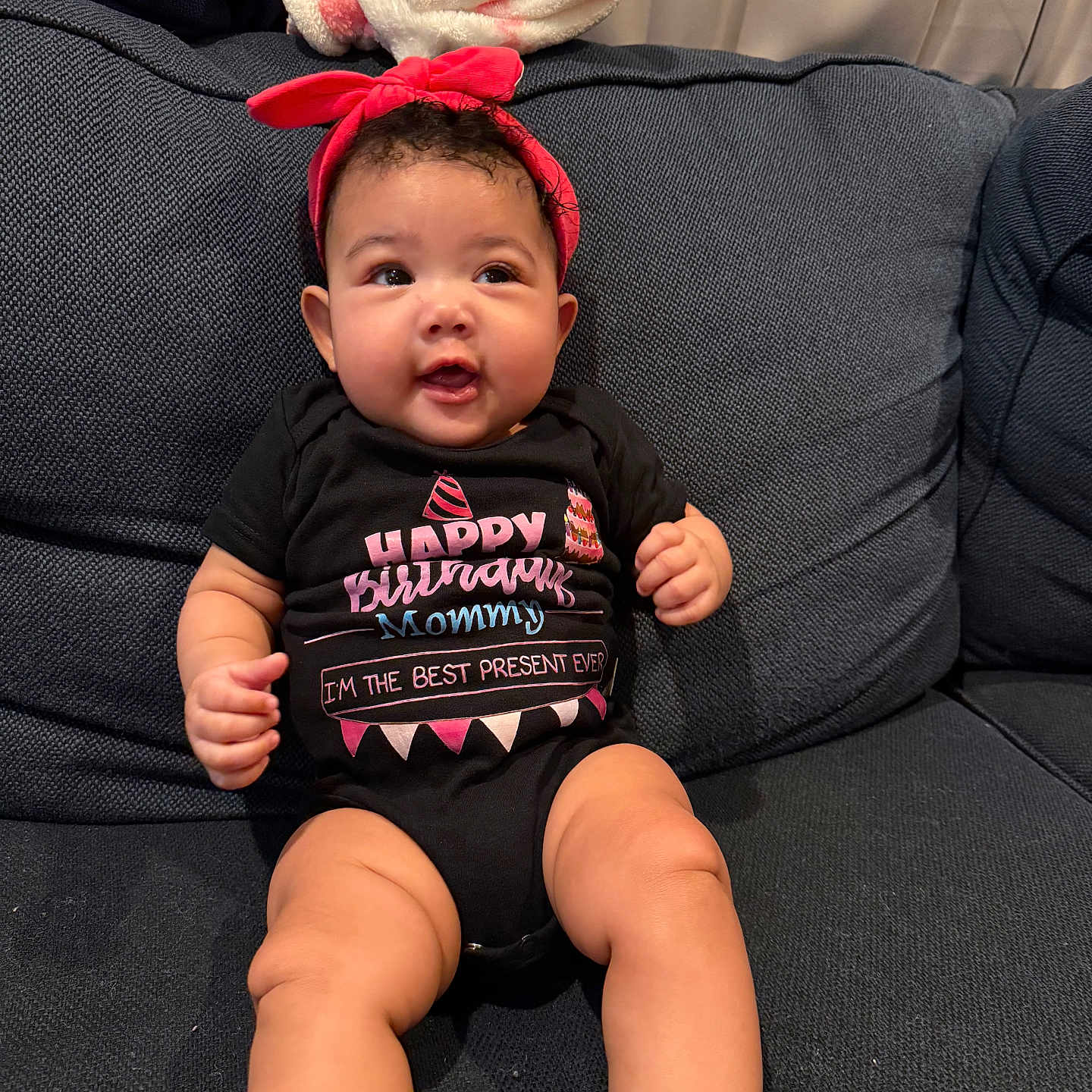 Zoey joined the competition — help win amazing prizes! baby, child, infant, sitting, couch, headband, onesie, birthday, text, blanket, happy, cute, indoors, portrait, smile, skin, furniture, clothing, cozy, comfort