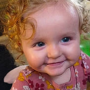 Athena is registered to the contest to win money with this photo: child, toddler, curly_hair, smile, blue_eyes, face, portrait, baby, cute, happy, indoors, clothing, floral_pattern, close_up, person, infant, young_child, cheeks, joy, innocence