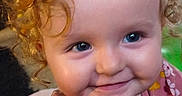 Athena is registered to the contest to win money with this photo: baby, blue_eyes, cheeks, child, close_up, clothing, curly_hair, cute, face, floral_pattern, happy, indoors, infant, innocence, joy, person, portrait, smile, toddler, young_child