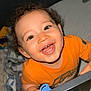 Alan joined the competition — help win amazing prizes! baby, bed, blanket, blue_pacifier, child, crib, curly_hair, cute, expression, face, happy, indoor, infant, looking_up, orange_shirt, person, playful, smiling, stuffed_toy, toddler