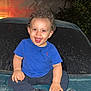 Alan is registered to the contest to win money with this photo: blue_shirt, car, casual_clothing, child, curious, curly_hair, dirt, expression, footwear, happy, hood, joyful, night, outdoor, person, sitting, smiling, toddler, vehicle, young_child