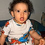 bedroom, blanket, child, clothing, curious, curly_hair, cute, expression, face, foot, hand, home, indoor, pajamas, person, sesame_street, sitting, soft_lighting, toddler, young_child