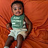 baby, child, smiling, sitting, bib, clothing, socks, shorts, orange_couch, furniture, face, person, indoors, happy, cute, home, infant, expression, head, seated