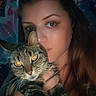 Cybelle a rejoint le concours — aidez-le/la à gagner de superbes lots ! woman, cat, tabby_cat, selfie, portrait, face, eyes, tattoo, long_hair, animal, pet, indoor, dark_background, tapestry, floral_pattern, hand, holding, closeup, expression, feline