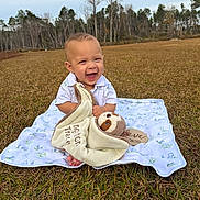 Kingston joined the competition — help win amazing prizes! baby, child, smiling, blanket, plush_toy, sloth, grass, outdoor, nature, field, trees, sky, happy, cute, infant, clothing, person, sitting, toy, playful