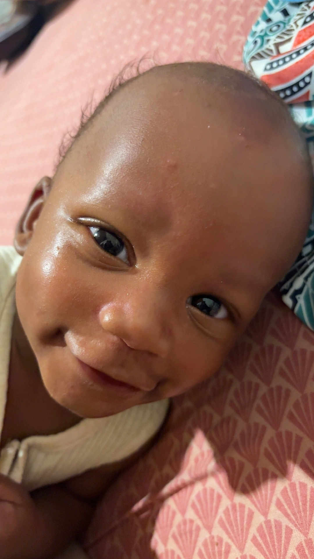 Jahylan participe au concours pour gagner de l'argent avec cette photo : baby, smiling, face, close_up, infant, child, skin, eyes, joyful, lying_down, patterned_surface, pink, cute, portrait, young_child, happy, person, indoors, head, expression