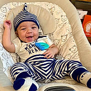 Paxton joined the competition — help win amazing prizes! baby, infant, smiling, striped_clothing, hat, teething_toy, baby_seat, cushion, bear_pattern, happy, child, cute, indoor, person, footwear, sock, relaxed, portrait, playful, young