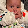 baby, infant, child, portrait, face, eyes, hand, blanket, fleece, onesie, bundled_up, cozy, sitting, lying_down, indoors, couch, colorful, close_up, looking_at_camera, cute