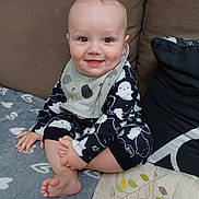 Rupert joined the competition — help win amazing prizes! baby, child, smiling, sitting, pajamas, bib, couch, cushion, blanket, foot, hand, face, happy, indoors, infant, cute, cozy, clothing, person, portrait
