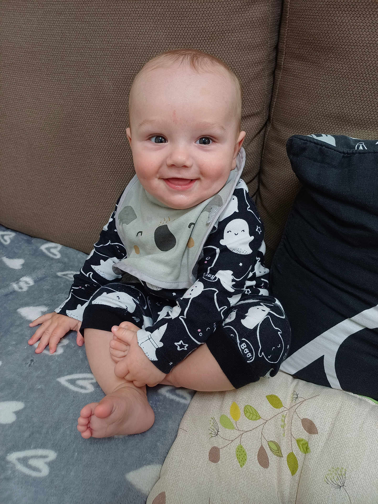 Rupert joined the competition — help win amazing prizes! baby, child, smiling, sitting, pajamas, bib, couch, cushion, blanket, foot, hand, face, happy, indoors, infant, cute, cozy, clothing, person, portrait