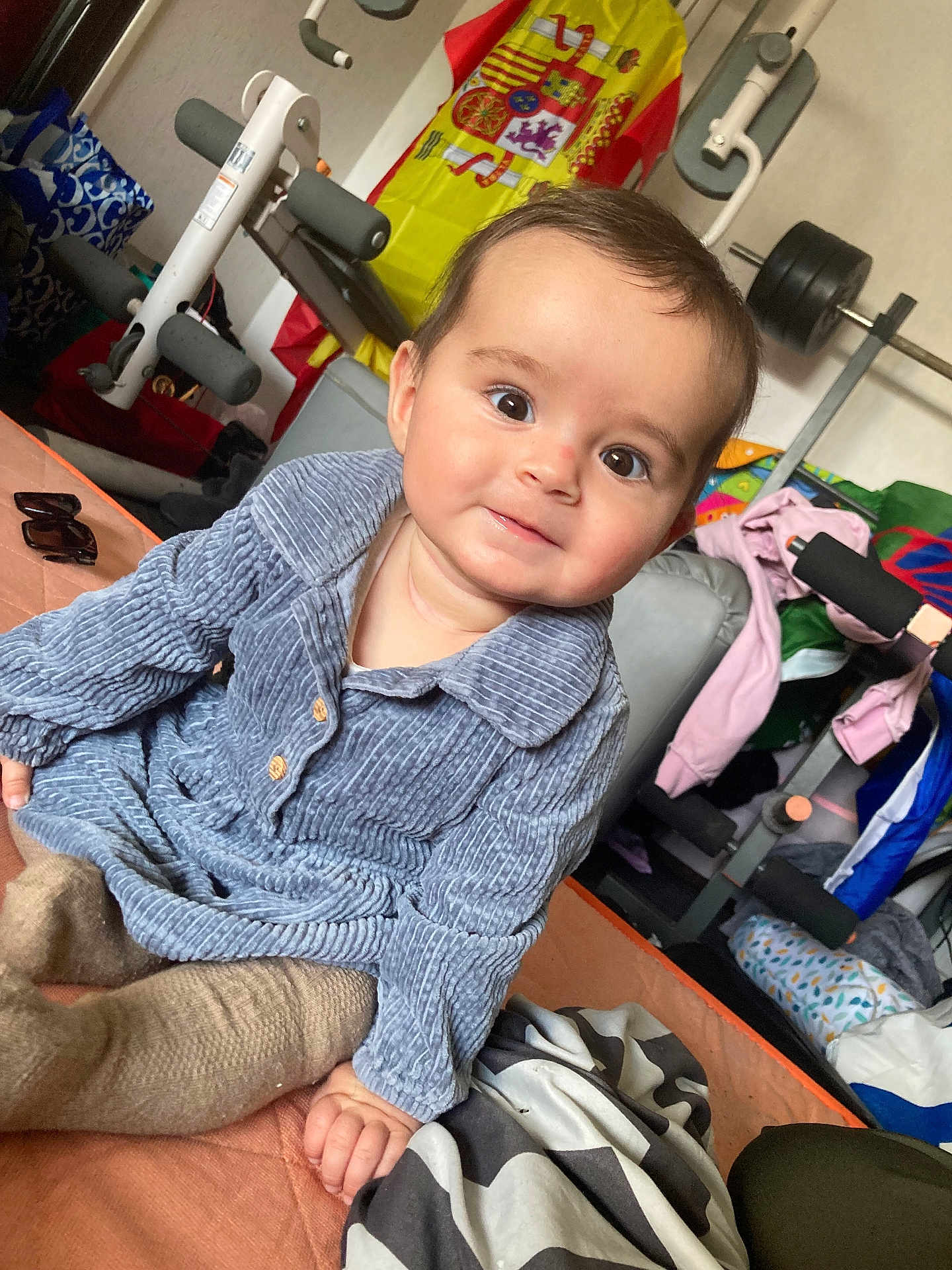 Katalëya a rejoint le concours — aidez-le/la à gagner de superbes lots ! baby, child, indoor, portrait, smile, corduroy, blue_clothing, bed, blanket, gym_equipment, weights, flag, spanish_flag, sunglasses, clothing, person, face, hand, seated, curly_hair