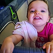Riley is registered to the contest to win money with this photo: toddler, child, playpen, blanket, smile, hand, face, curiosity, indoor, clothing, pink_shirt, baby, furniture, soft_lighting, expression, happy, young_child, person, closeup, home