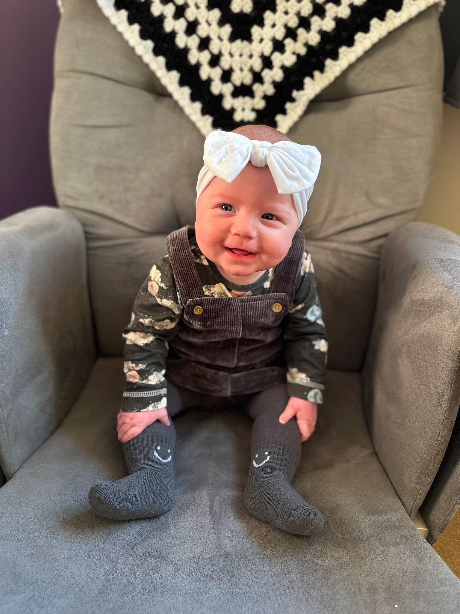 Astrid joined the competition — help win amazing prizes! baby, baby_toddler_clothing, cap, child, comfort, costume_hat, eye, face, facial_expression, glasses, head, headwear, human_body, jacket, joy, lap, outerwear, person, sitting, sleeve