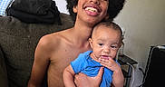 Honestii is registered to the contest to win money with this photo: teenager, baby, afro, smiling, blue_clothing, couch, indoor, family, child, holding, happy, person, casual, home, furniture, sitting, expression, portrait, candid, relaxed