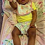 Leilani joined the competition — help win amazing prizes! baby, infant, blanket, floral_pattern, pink_slippers, yellow_shirt, shorts, bib, hand, face, hair_bow, carpet, indoor, person, cute, reaching, lying_down, plush, child, toddler